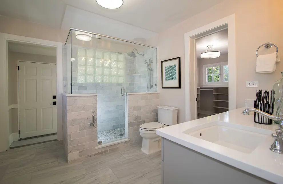 Primary bath with a frameless glass shower, marble-look tile and a quartz vanity