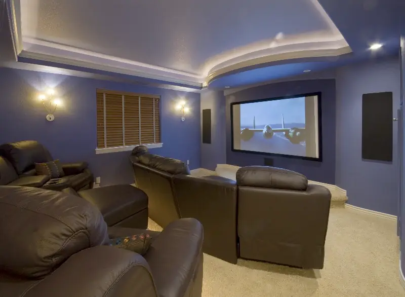Finished basement theater with blue walls and cove lighting