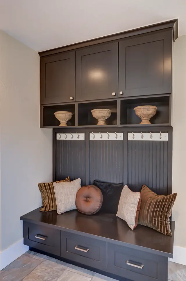 Dark-stained mudroom built-in bench with cubbies and coat hooks