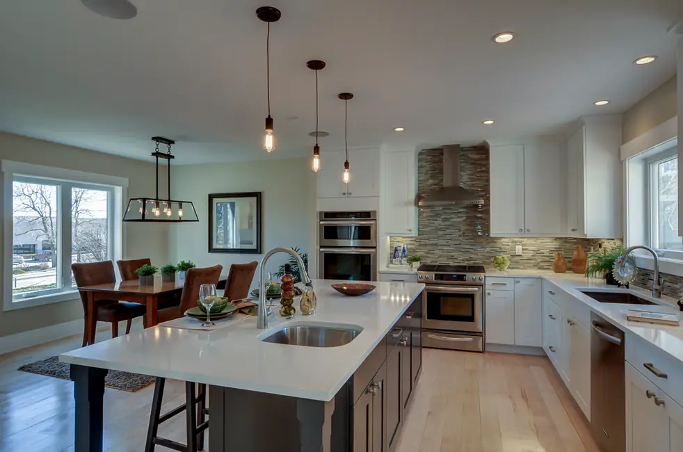 Open kitchen with an island, pendant lights and a stainless double oven